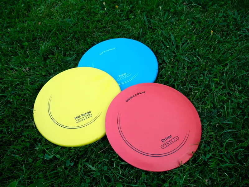 Three disc golf discs, a putter, a midrange and a driver, lying on grass